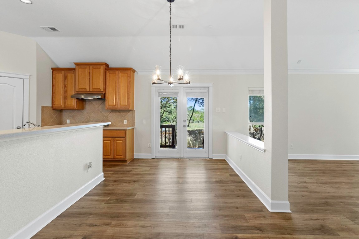 10805 Ariock Lane Austin, TX 78739 - Photo 5 of 40 Kitchen with brown cabinetry, light countertops, decorative light fixtures, a chandelier, and dark wood finished floors