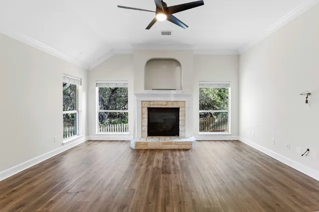 an empty room with wooden floor a fireplace and windows