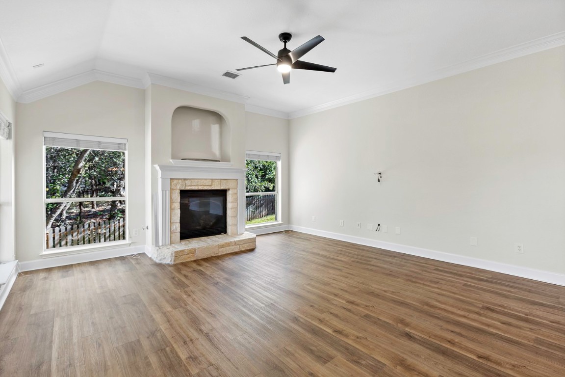 10805 Ariock Lane Austin, TX 78739 - Photo 9 of 40 Unfurnished living room with ornamental molding, dark wood-type flooring, lofted ceiling, ceiling fan, and a fireplace