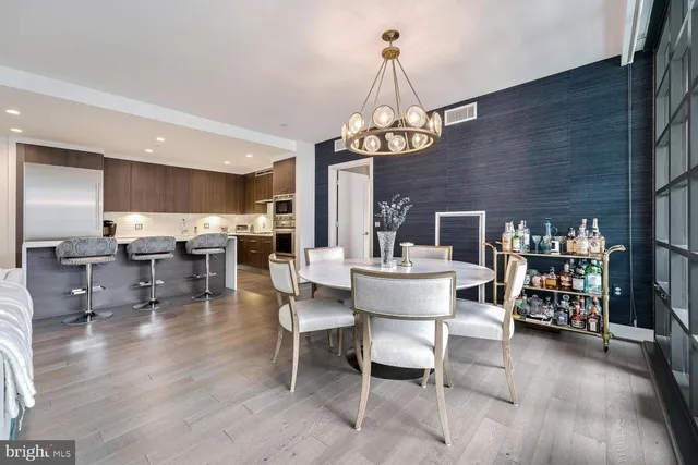 a dining room with wooden floor a chandelier a glass table and chairs