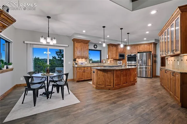 a kitchen with stainless steel appliances kitchen island granite countertop a table chairs and a refrigerator