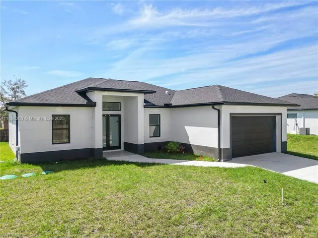 a view of a house with a yard and a large tree