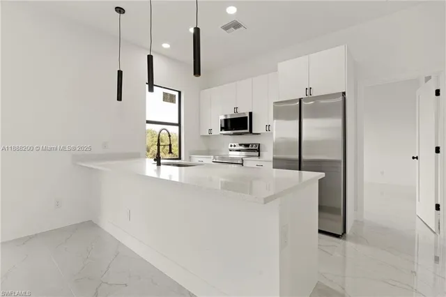 a kitchen with kitchen island a counter space a sink appliances and cabinets