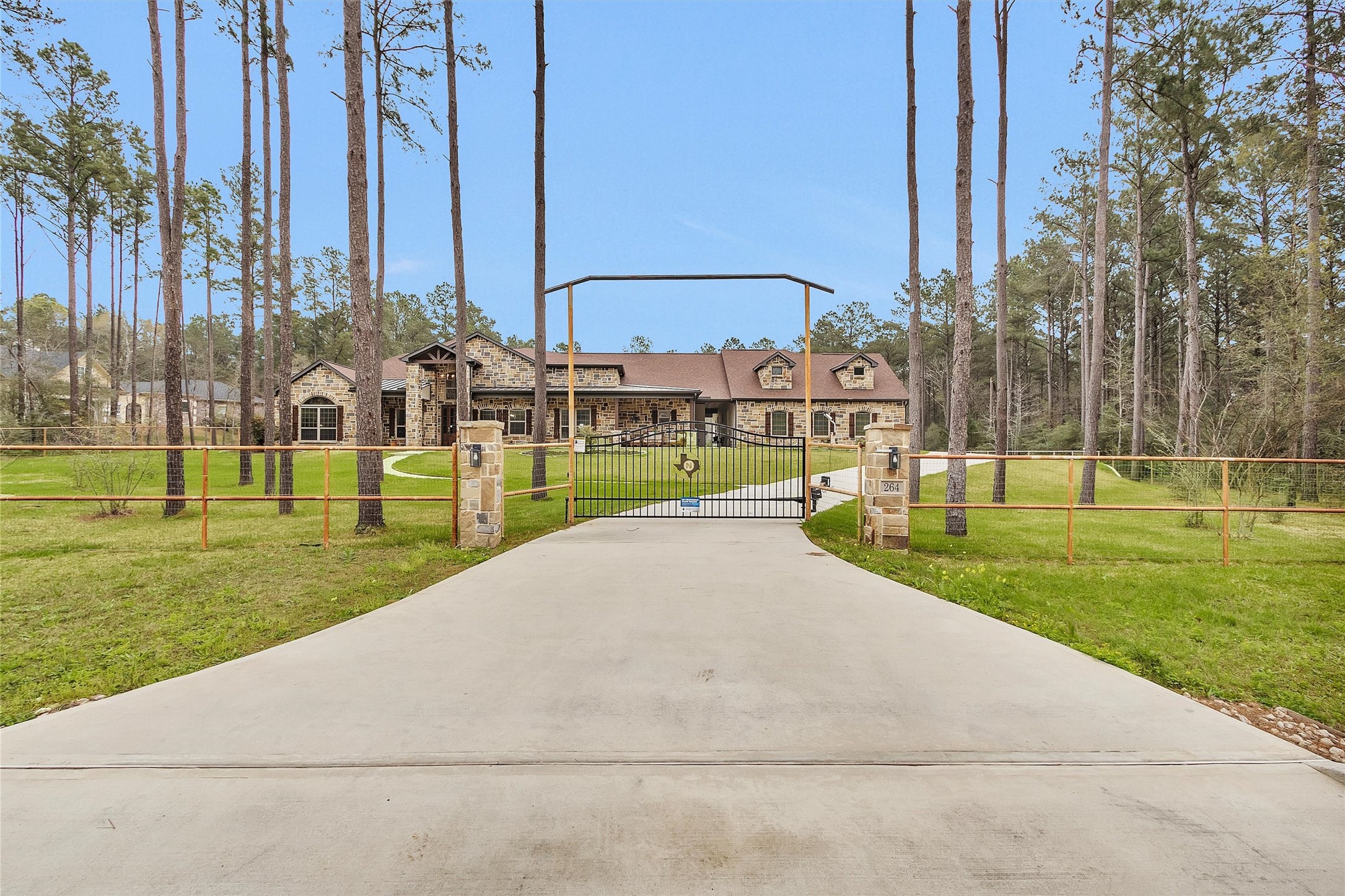 264 Grey Feather Road Huntsville, TX 77340 - Photo 2 of 31 Expansive concrete driveway leading to oversized garage and equipment area.