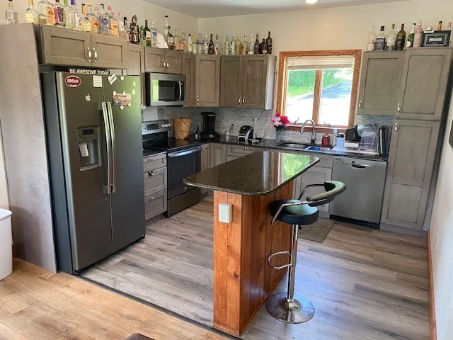a kitchen with kitchen island a counter top space a sink a refrigerator and a dishwasher