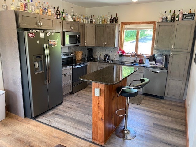 a kitchen with kitchen island a counter top space a sink a refrigerator and a dishwasher