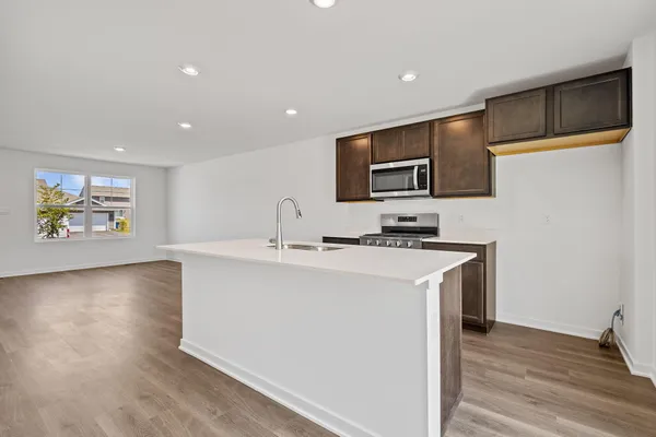 a kitchen with stainless steel appliances granite countertop a stove a sink and a refrigerator with wooden floor