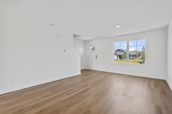 a view of an empty room with a window and wooden floor