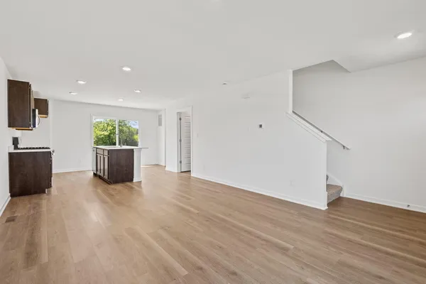a view of a livingroom with wooden floor and kitchen space