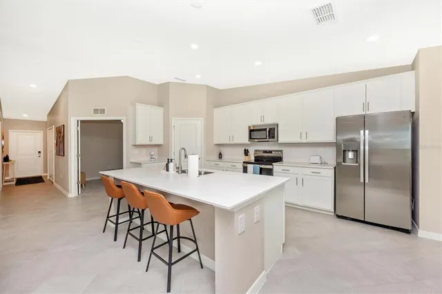 a kitchen with stainless steel appliances a refrigerator a stove a sink dishwasher with a dining table and chairs