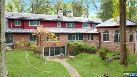 a view of a brick house with a yard potted plants and a table