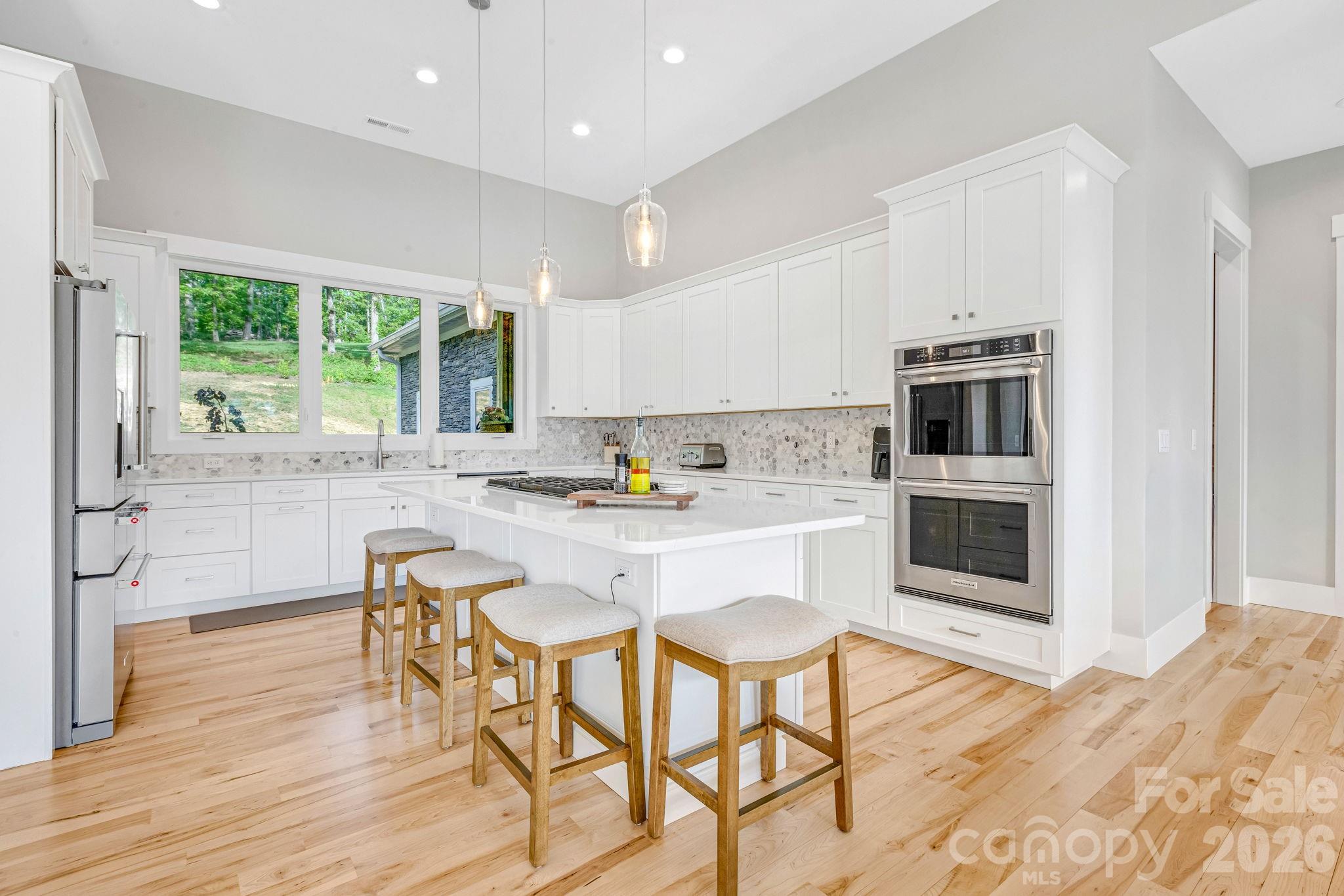 128 Saddle Ridge Drive Alexander, NC 28701 - Photo 7 of 33 a kitchen with stainless steel appliances granite countertop a stove a sink a microwave and a dining table with wooden floor