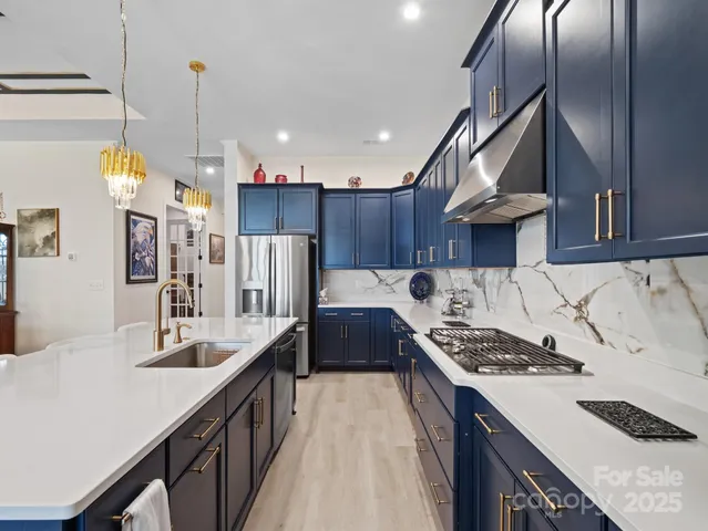 a kitchen with stainless steel appliances kitchen island granite countertop a sink stove and refrigerator