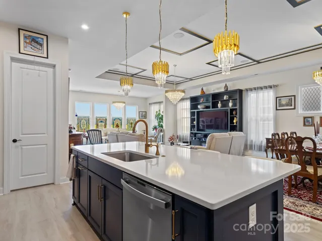a kitchen with stainless steel appliances granite countertop a sink a counter space and living room view
