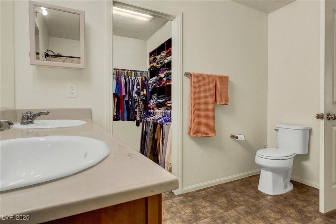 9236 Keystone Ridge Avenue Las Vegas, NV 89148 - Photo 26 of 38 Bathroom featuring toilet, double vanity, baseboards, and a walk in closet