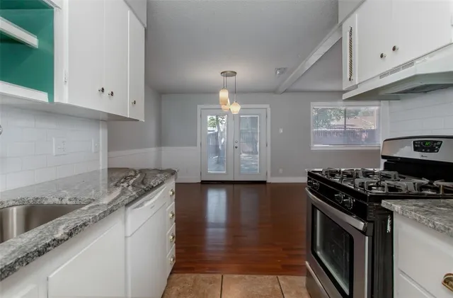 a kitchen with granite countertop a stove top oven a sink dishwasher and cabinets with wooden floor