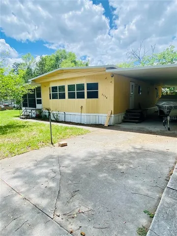 a view of a house with a yard and a large tree