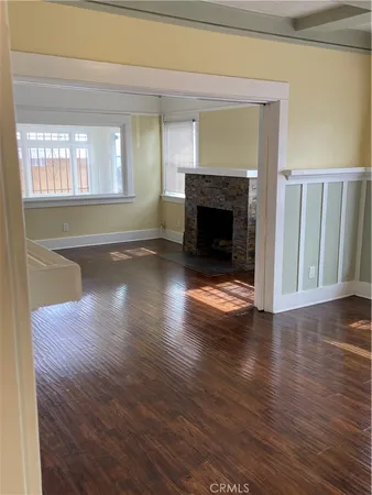 a view of an empty room with wooden floor fireplace and a window