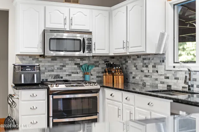 a kitchen with granite countertop white cabinets stainless steel appliances and a sink