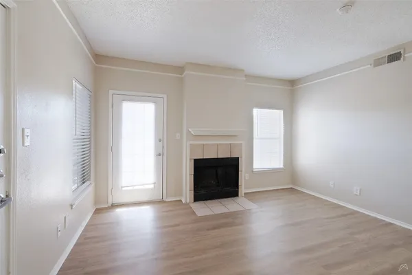 an empty room with wooden floor fireplace and windows