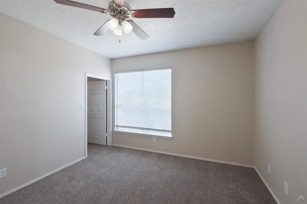 an empty room with a chandelier fan and windows
