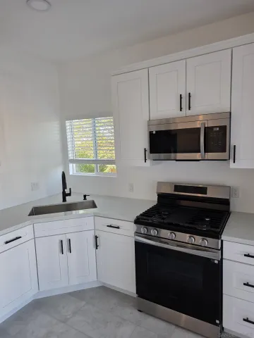 a kitchen with white cabinets and black appliances