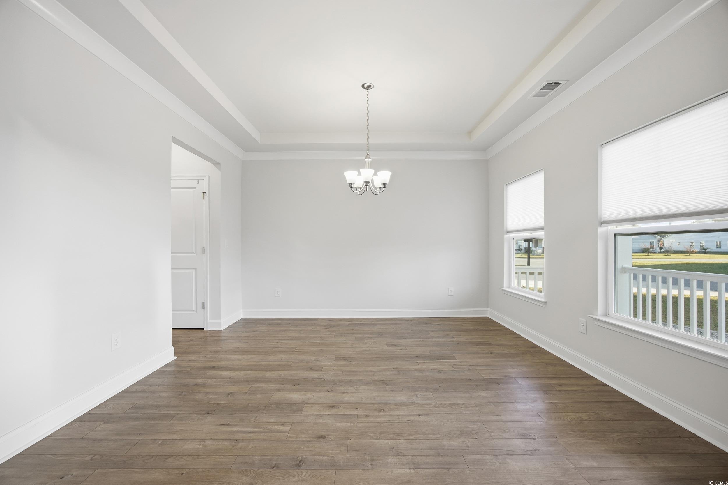 386 Harbison Circle Myrtle Beach, SC 29579 - Photo 5 of 34 Empty room featuring a raised ceiling, wood finished floors, and a chandelier