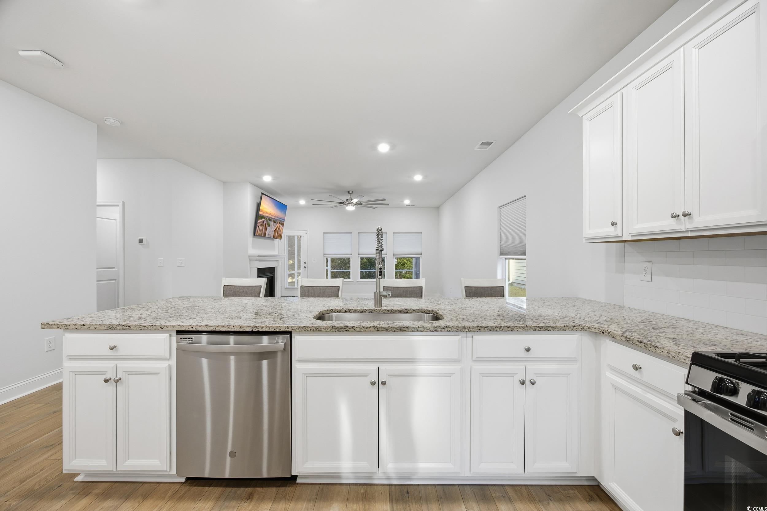 386 Harbison Circle Myrtle Beach, SC 29579 - Photo 8 of 34 Kitchen with white cabinetry, dishwasher, recessed lighting, light wood-type flooring, and a fireplace