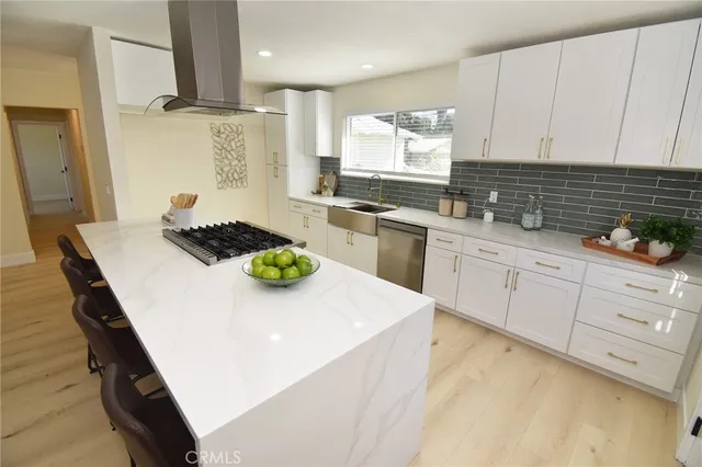 a kitchen with stainless steel appliances a stove a white cabinets a sink and a refrigerator