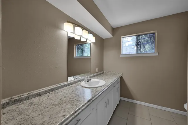 a bathroom with a granite countertop sink and a window