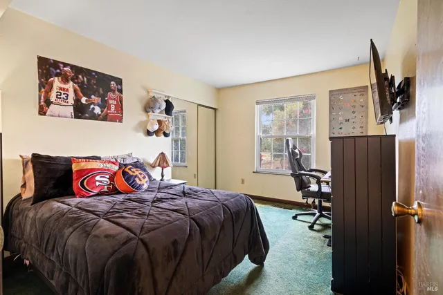 a bedroom with a bed and a flat tv screen next to a window