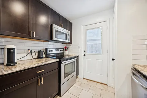 a kitchen with granite countertop a sink stove and cabinets