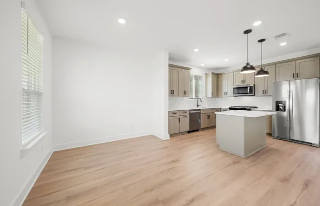 a view of kitchen with stainless steel appliances granite countertop a stove top oven a sink and a refrigerator