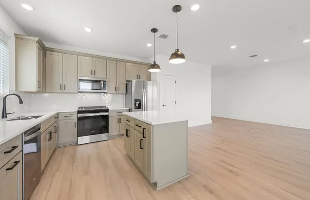 a kitchen with a refrigerator a sink and wooden floor