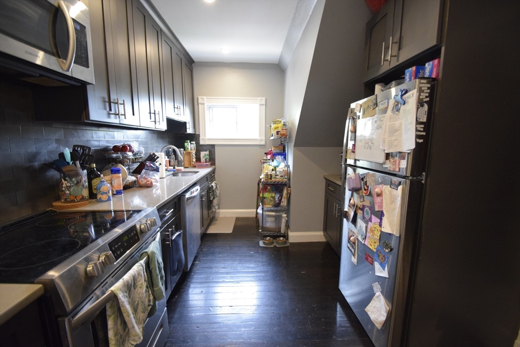 33-35 Ridgemont Street, Unit 3 Boston, MA 02134 - Photo 4 of 12 a kitchen with stainless steel appliances granite countertop a refrigerator a sink dishwasher a stove and white countertops with wooden floor