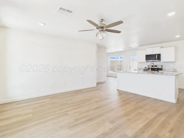 a view of a kitchen with a sink dishwasher a refrigerator with white cabinets and wooden floor