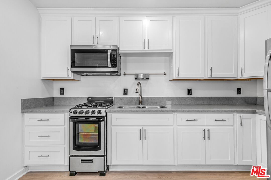 123 North Reno Street Los Angeles, CA 90026 - Photo 12 of 28 a kitchen with granite countertop white cabinets and stainless steel appliances