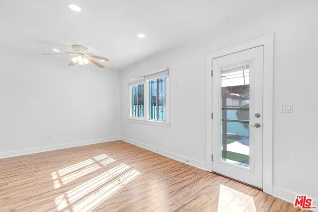 a view of an empty room with window and wooden floor