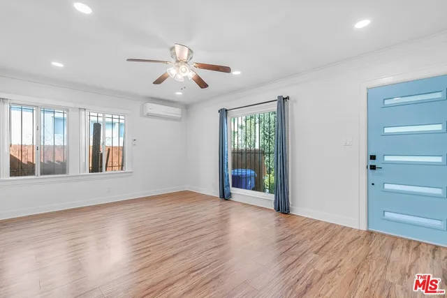 a view of an empty room with window and wooden floor