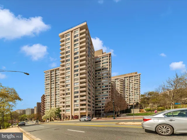 a front view of a building with lot of street and trees