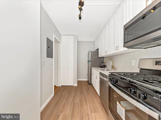 a kitchen with stainless steel appliances a stove a sink and white cabinets