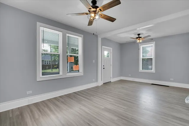 a view of an empty room with window and wooden floor