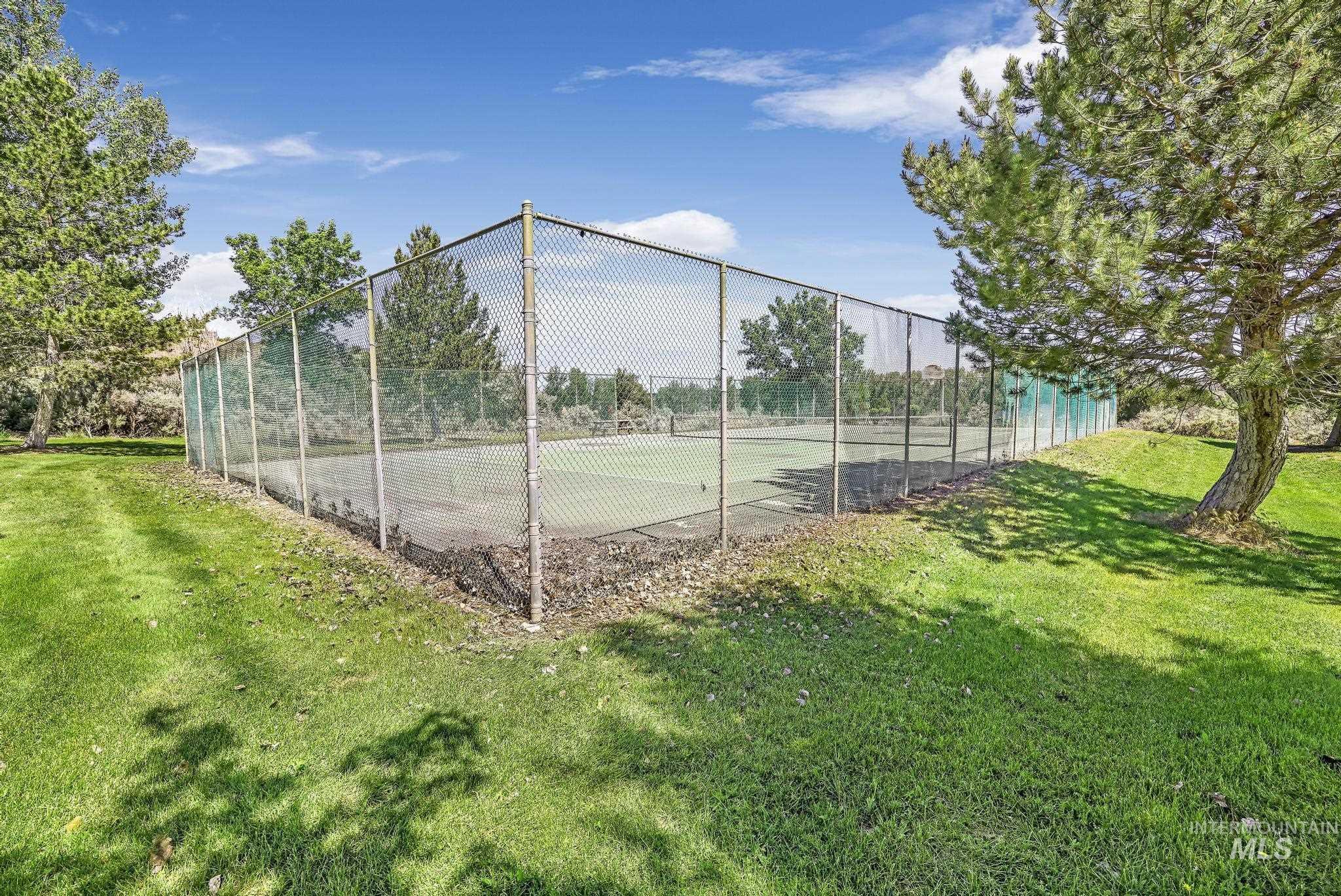 4485 Silver Creek Road Buhl, ID 83316 - Photo 44 of 49 Outdoor tennis court with chain-link fencing, surrounded by mature trees and manicured lawn