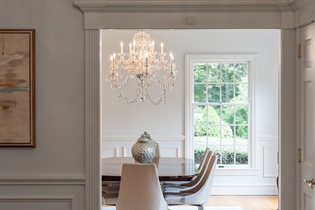 a view of a dining room with furniture a chandelier and large windows