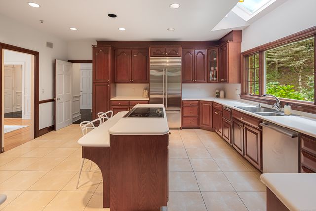 a large kitchen with kitchen island granite countertop a sink a counter top space appliances and cabinets
