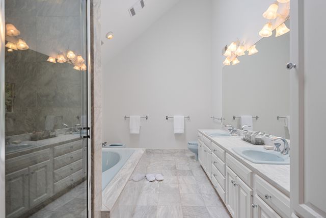 a bathroom with a double vanity sink a toilet and shower