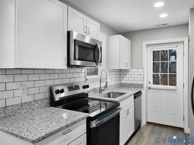 a kitchen with granite countertop a sink stove and microwave