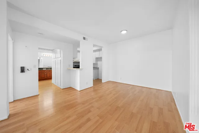 a view of a big room with wooden floor and kitchen view