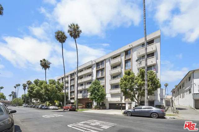 a view of a building and car parked on the side of road
