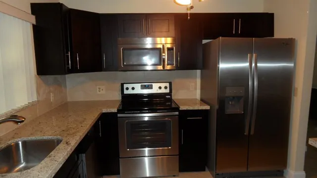 a kitchen with stainless steel appliances granite countertop a sink and a refrigerator